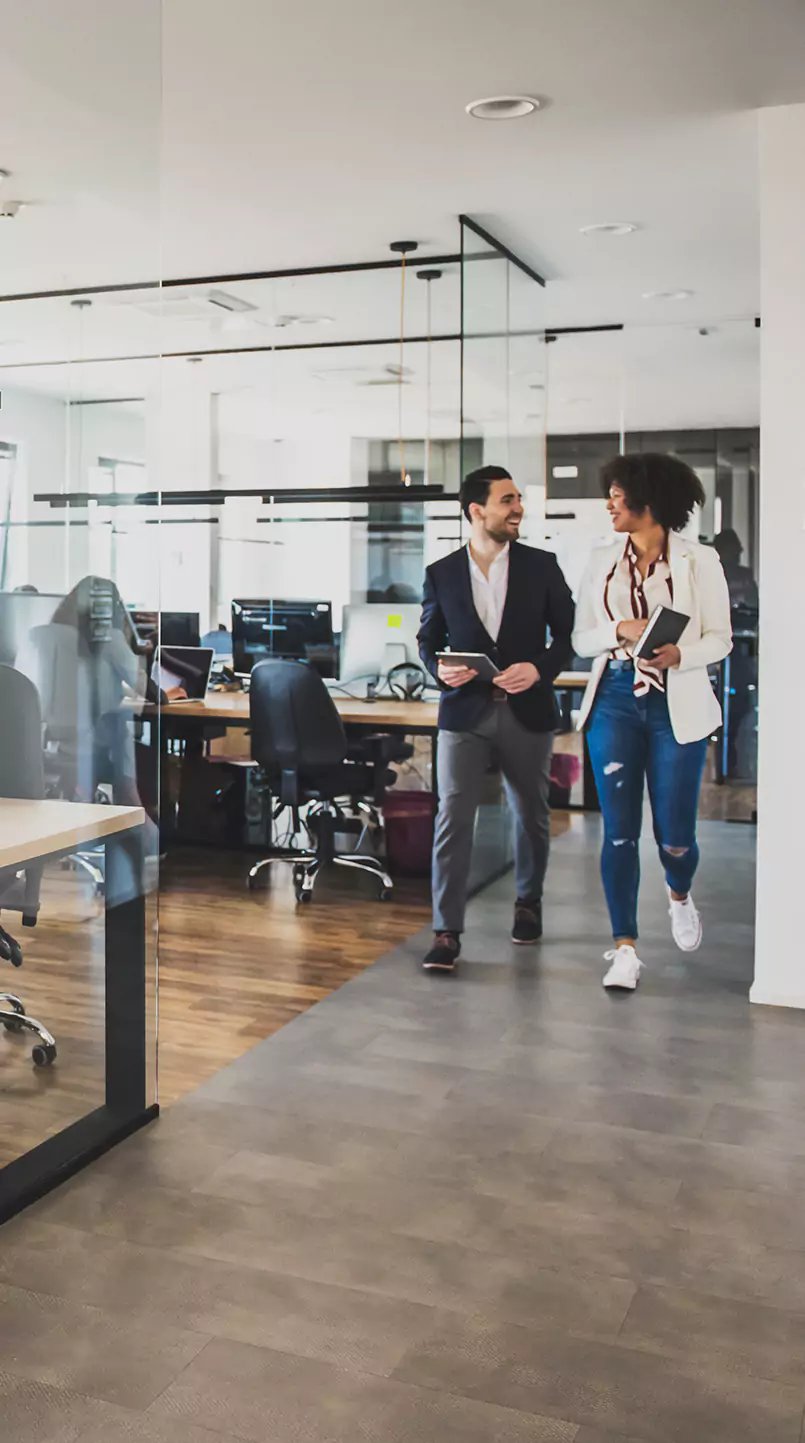 Zwei Versicherungsangestellte laufen durch ein modernes Büro.