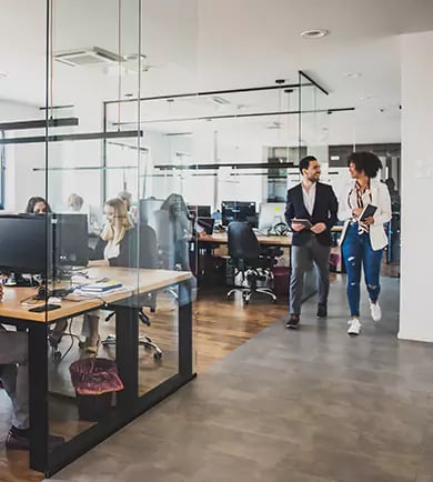Zwei Versicherungsangestellte laufen durch ein modernes Büro.