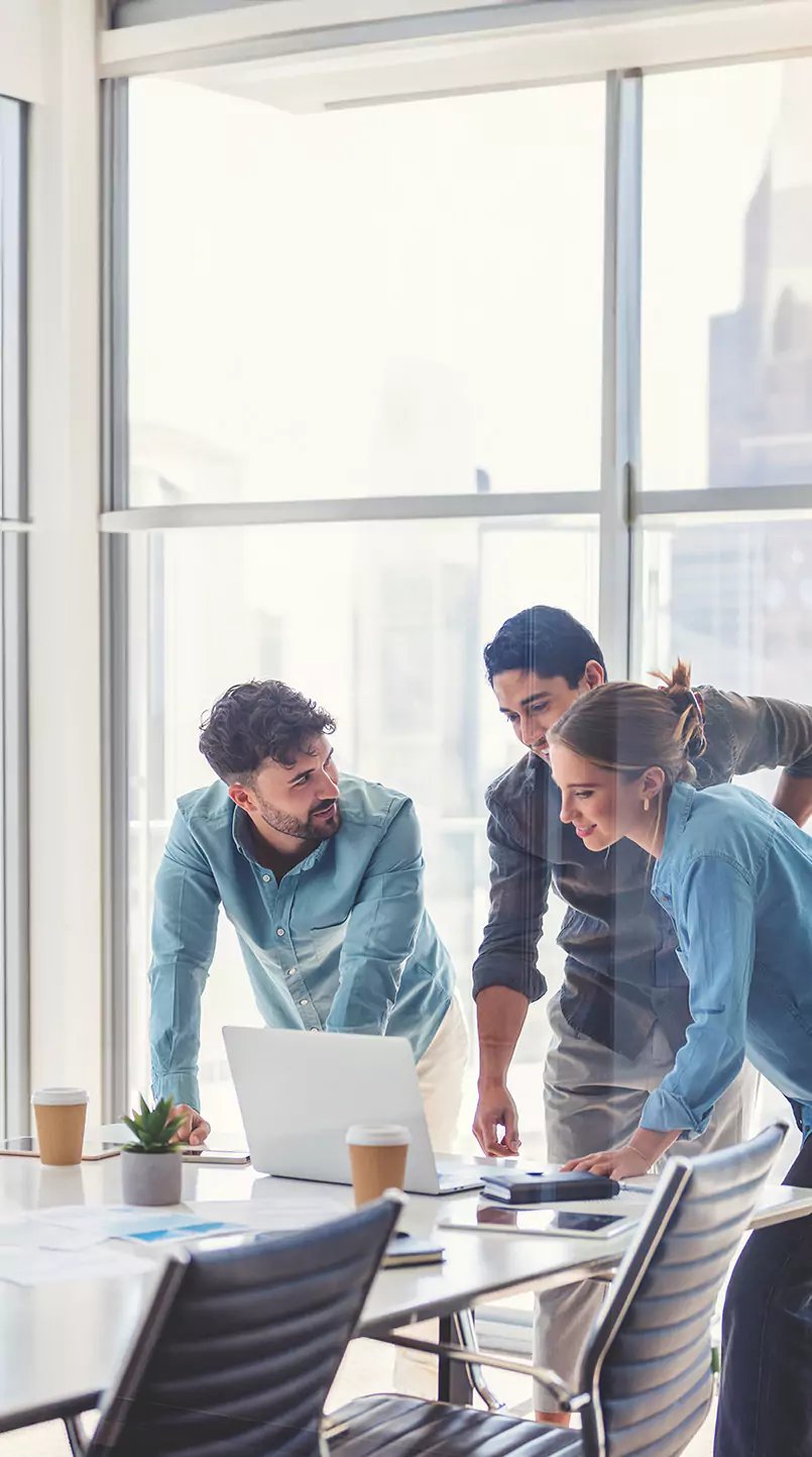 Three employees in a meeting room discussing business processes.